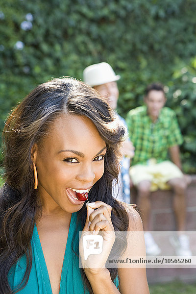 Smiling woman eating cherry in backyard