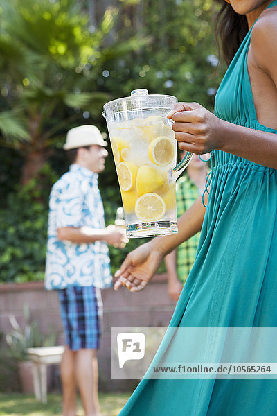 Woman holding pitcher of lemonade at backyard barbecue