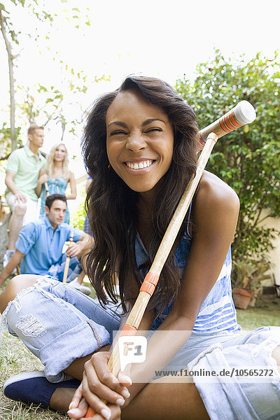 Smiling woman holding croquet mallet in backyard