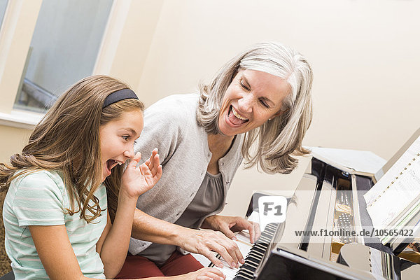 Kaukasische Großmutter und Enkelin spielen Klavier