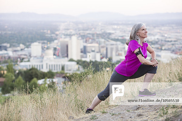 Caucasian woman stretching on hilltop over Salt Lake City  Utah  United States