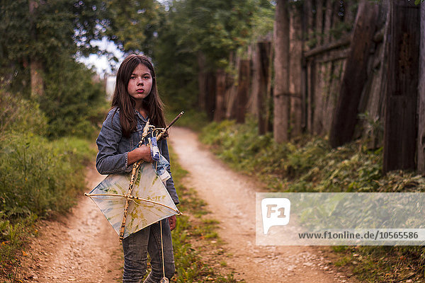 Caucasian teenage girl carrying kite on dirt road