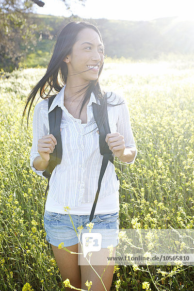 Gemischtrassige Frau trägt Rucksack im Feld