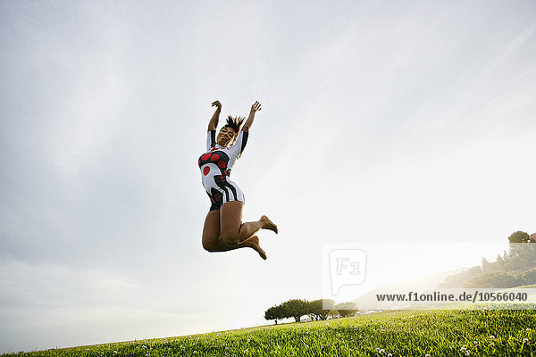 Schwarze Frau springt vor Freude auf einem Feld