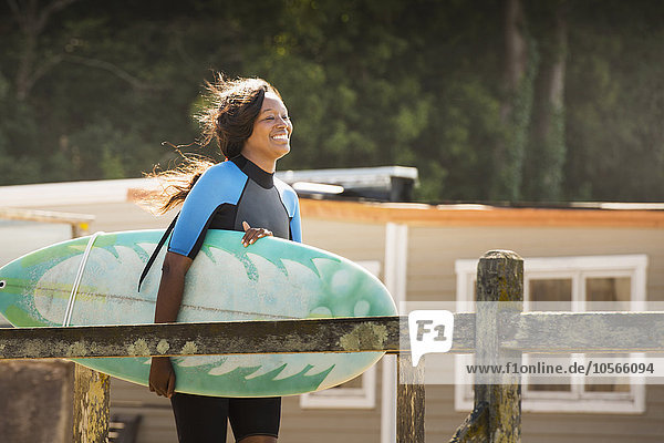Afroamerikanische Frau trägt Surfbrett im Freien