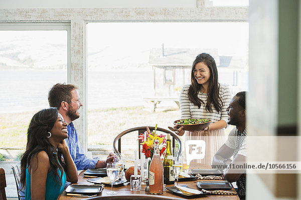 Frau serviert Freunden bei einer Dinnerparty