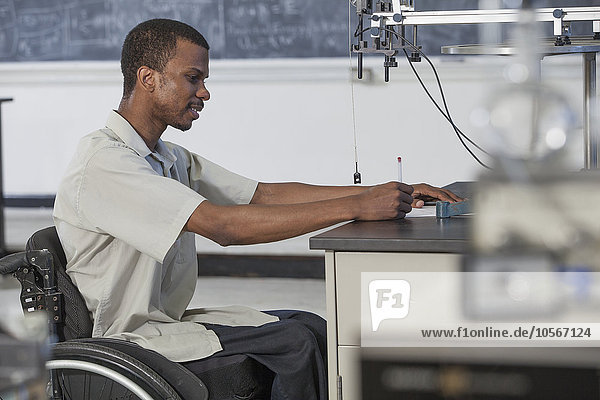 African American paraplegic student working in science classroom