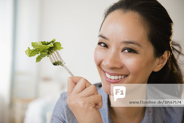 Chinesische Frau isst Salat