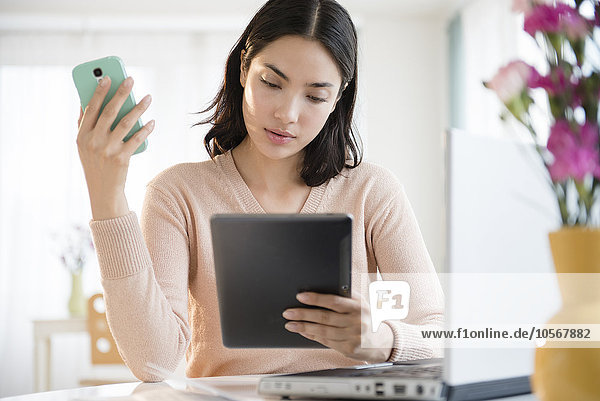 Hispanic woman using cell phone and digital tablet