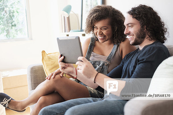 Couple using digital tablet on sofa