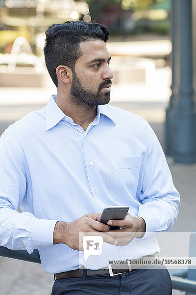 Indischer Geschäftsmann benutzt Mobiltelefon in der Stadt