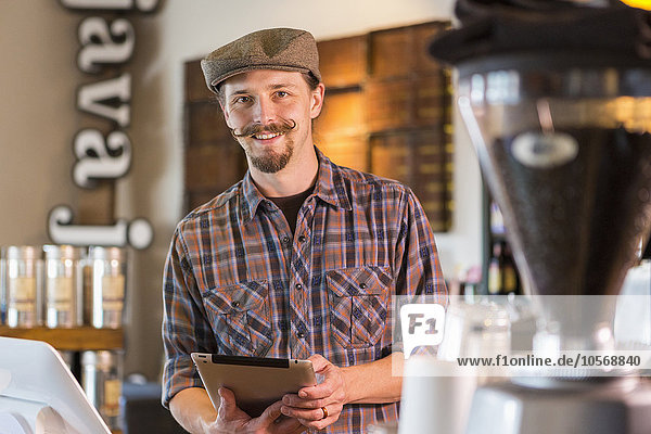 Caucasian barista holding digital tablet in cafe