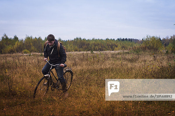 Caucasian man riding bicycle in field