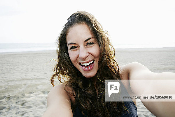 Gemischtrassige Frau macht Selfie am Strand