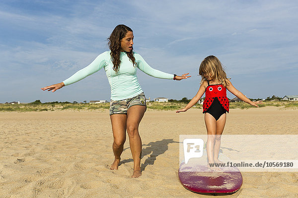 Mother teaching daughter to surf at beach