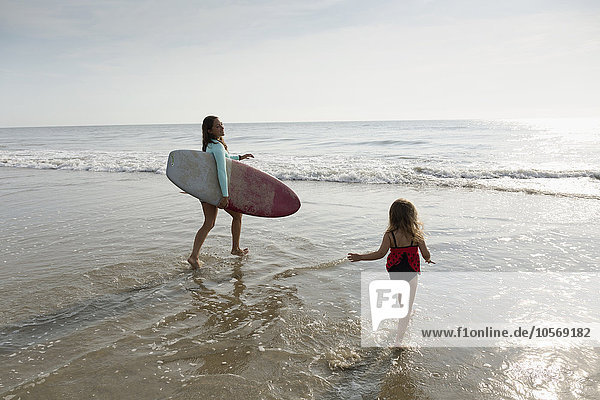 Mutter und Tochter spielen in den Wellen am Strand