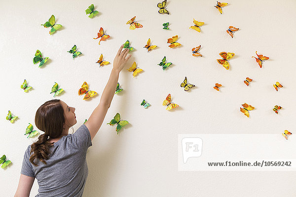 Gemischtrassige Frau dekoriert Wand mit Schmetterlingen