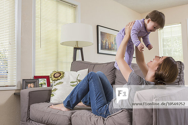 Mixed race mother playing with baby daughter on sofa