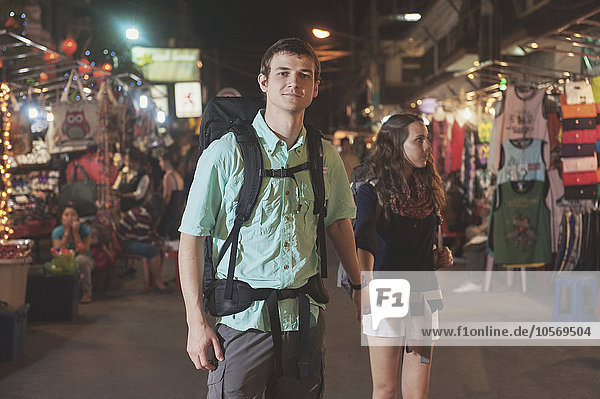 Caucasian tourists holding hands in market at night