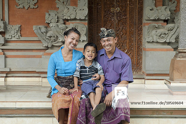 Asiatische Mutter  Vater und Sohn lächelnd vor verschnörkeltem Gebäude