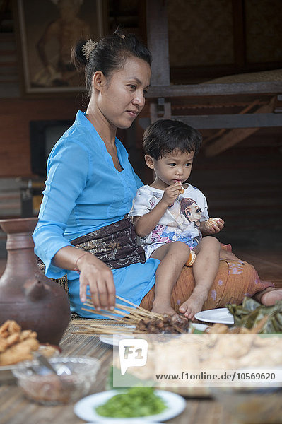 Asiatische Mutter und Sohn essen auf einer gewebten Matte