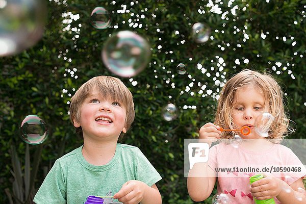 Junges Mädchen und Junge blasen Blasen  draußen