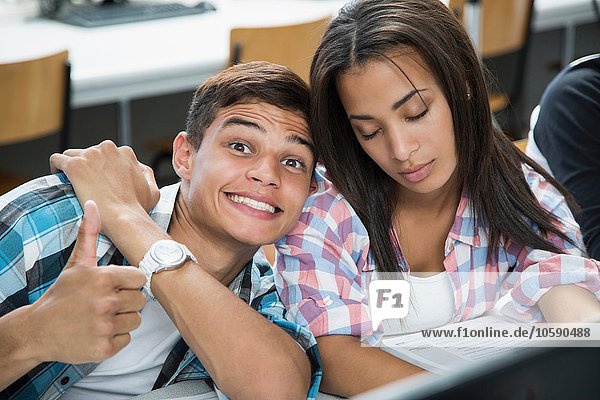 Porträt eines Teenagers mit käsigem Grinsen und einem Mädchen mit geschlossenen Augen in der Klasse.
