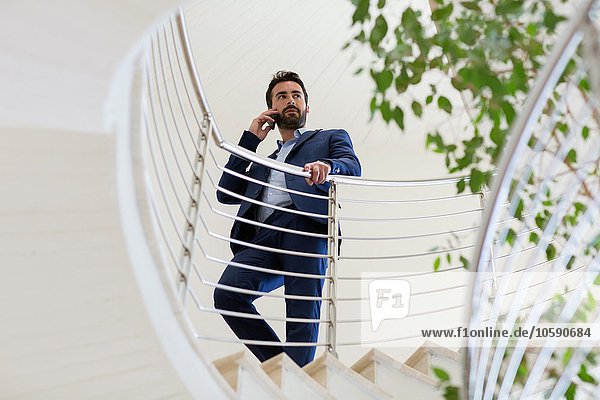 Junger Geschäftsmann im Gespräch auf dem Smartphone auf der Bürotreppe
