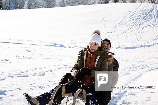 Senior couple sitting on sledge looking at camera smiling  Sattelbergalm  Tyrol  Austria