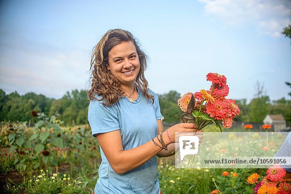 Portrait of female farm worker holding a bunch of fresh cut flowers