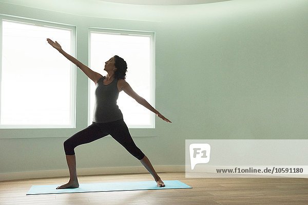 Mature woman doing yoga warrior pose in curved room