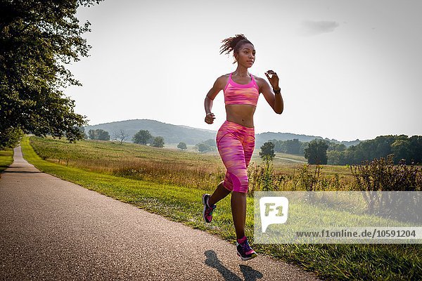 Young female runner running in rural park