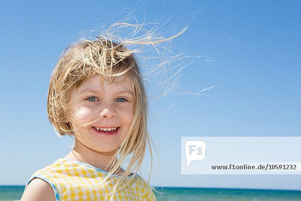 Porträt eines Mädchens mit blonden Flyaway-Haaren am Strand
