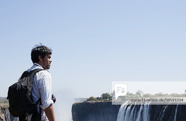 Mid adult man looking out at Victoria Falls  Zambia