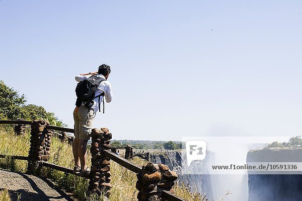 Mid adult man photographing Victoria Falls  Zambia