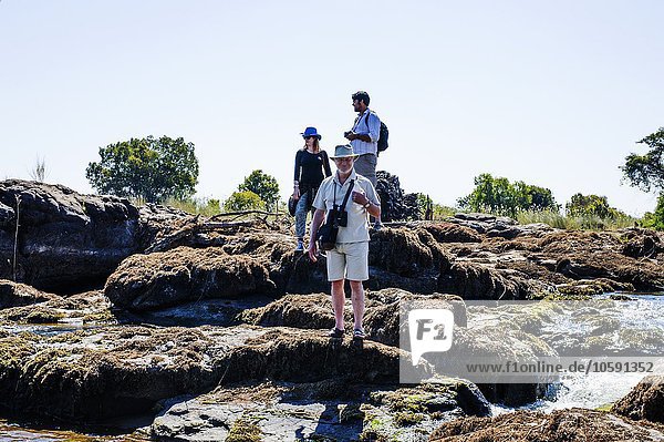 Ehepaar und reifer Mann auf Felsen,  in der Nähe von Victoria Falls,  Sambia