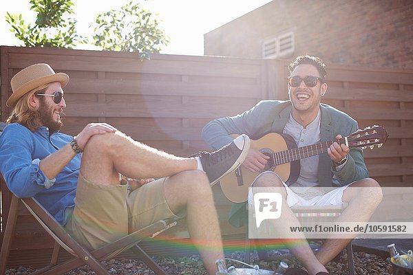 Zwei männliche Freunde beim Gitarrespielen auf der Dachparty