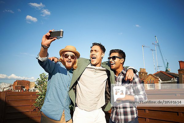 Drei männliche Freunde  die sich auf der Dachparty selbst fotografieren lassen