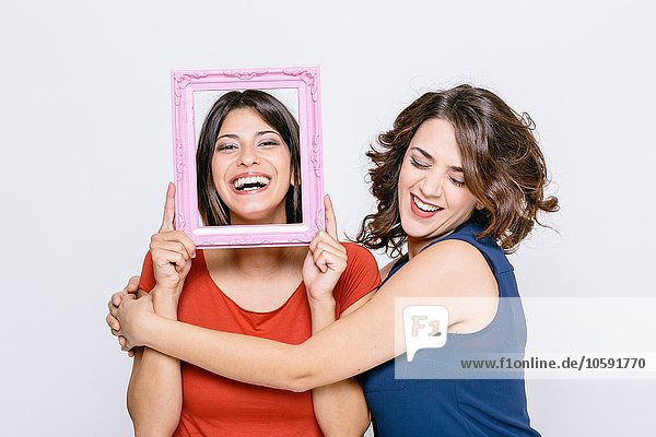 Lesbian couple fooling around with pink picture frame smiling