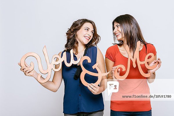 Lesbian couple holding the words you and me face to face smiling