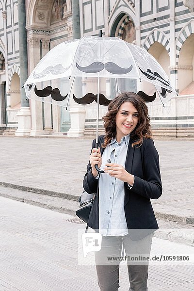 Junge Frau mit Regenschirm und lächelnder Kamera  Piazza Santa Maria Novella  Florenz  Toskana  Italien