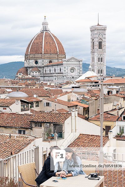 Lesbian couple sitting at table on roof terrace in front of Giotto's Campanile and Florence Cathedral  Tuscany  Italy