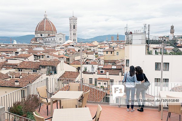 Rear view of lesbian couple standing of roof terrace looking at view of Giotto's Campanile and Florence Cathedral  Tuscany  Italy