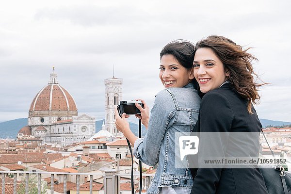 Lesbian couple taking photo of Florence Cathedral and Giotto's Campanile looking over shoulder smiling  Florence  Tuscany  Italy
