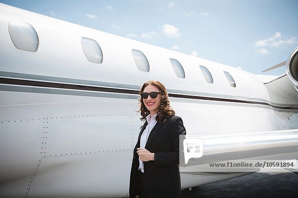 Portrait of female businesswoman and private jet at airport