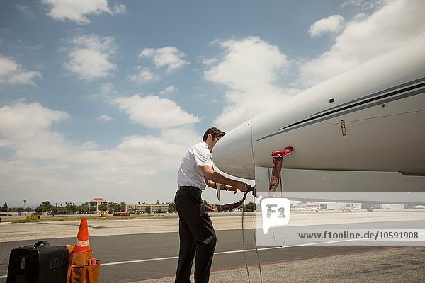 Male private jet pilot checking plane at airport