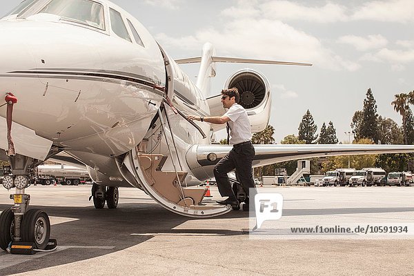 Male private jet pilot boarding plane at airport