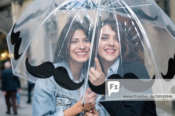 Lesbian couple underneath transparent umbrella looking at camera smiling  Florence  Tuscany  Italy