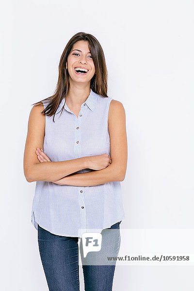 Young woman wearing shirt and skinny jeans arms crossed looking at camera smiling