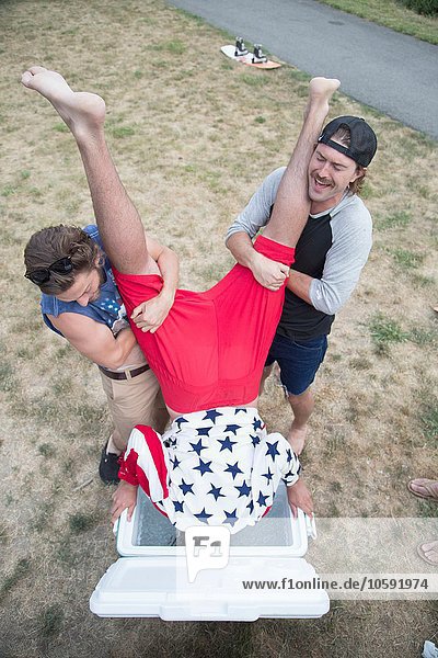 Zwei junge Männer tauchen ihren Freund am Independence Day  USA  in eine Kühlbox.